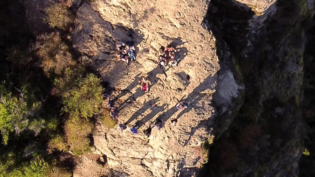 Overhead view of students grouped on top of a flat rocky shelf.