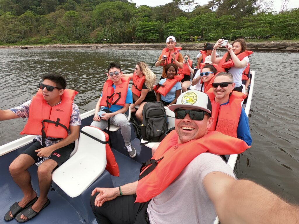 Students and staff in orange life vests enjoying an outboard boat trip.