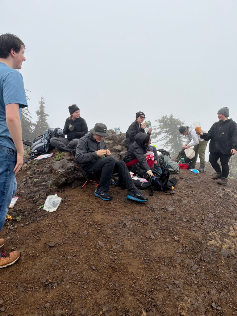 Stopping for a snack atop a rocky subalpine outcropping -- fog and low overcast obscure the view and it's good to relax for a while.