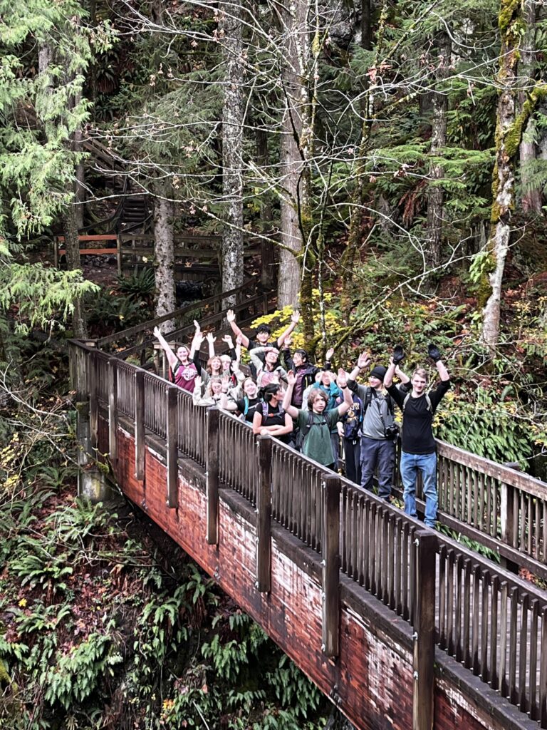 Students cross an aging footbridge over a river.