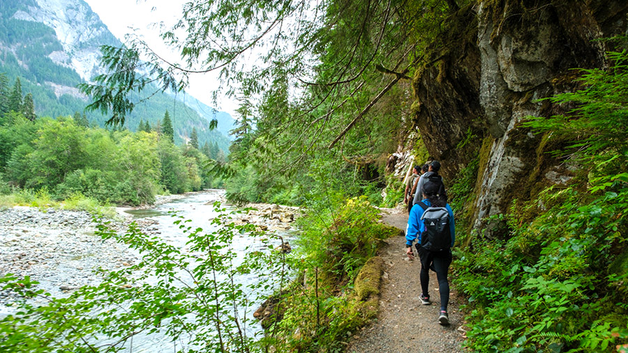 Hikers along the Middle Fork of the Snoqualmie River, with the river at a low level.