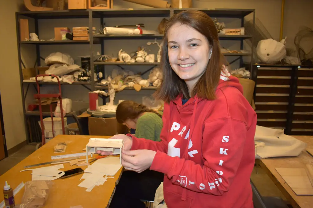 A student displays their work in an interior design class.