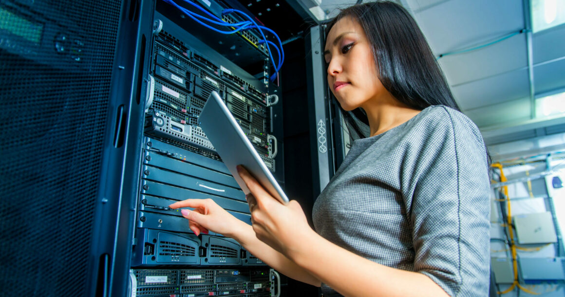 Young engineer businesswoman with tablet in network server room