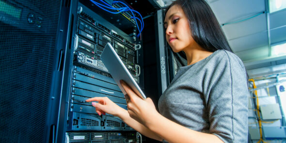 Young engineer businesswoman with tablet in network server room