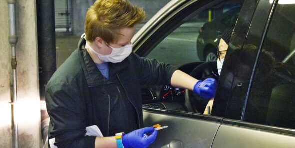 A masked nurse gets ready to deliver a flu vaccine at the drive-thru flu shot clinic