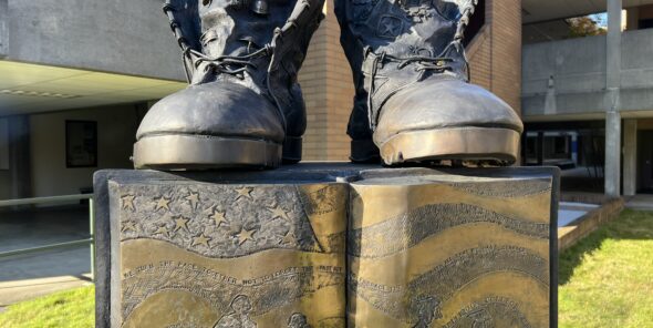 Two boots in bronze sit atop a bronze book