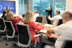 Two BC students demonstrate a wellness exercise to a group in a meeting room