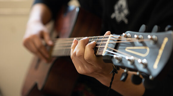 A close-up of hands strumming a guitar.