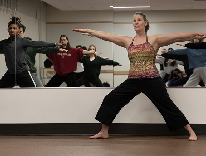 A professor leads a dance class in front of the mirror.