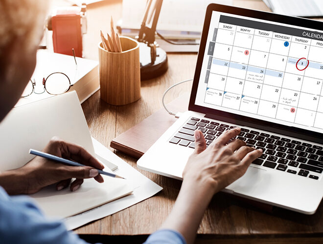 A person notes calendar dates on a laptop.