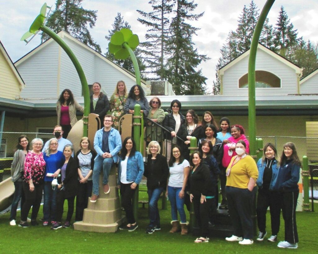 Members of the Early Learning Staff smiling for a photo in the Early Learning Center playground.