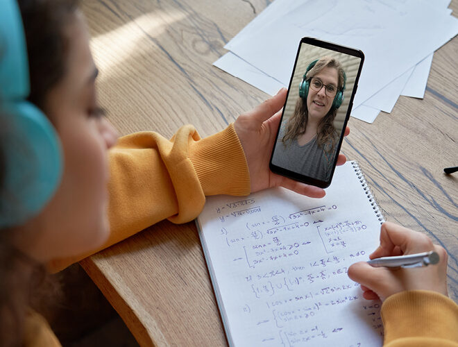 A student takes notes while on a remote call.