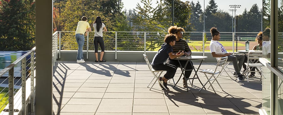 Students enjoying late sun on the second floor west balcony.