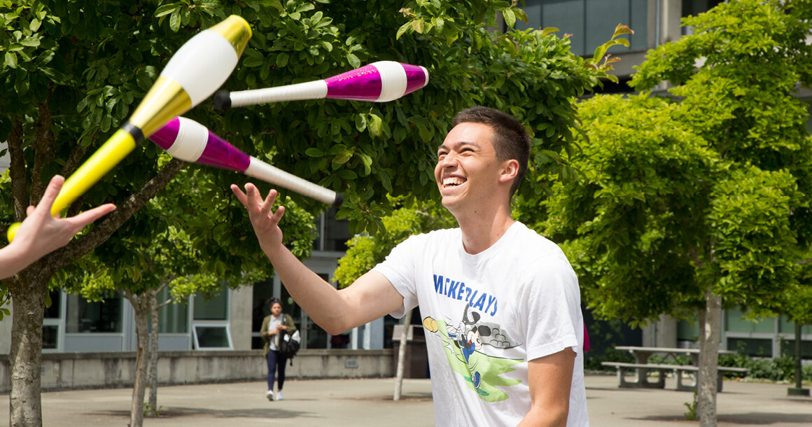 Two students juggle pins on BC's campus.