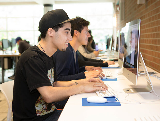 Students work in class on desktop computers.