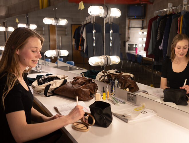 A theater student applies makeup backstage.