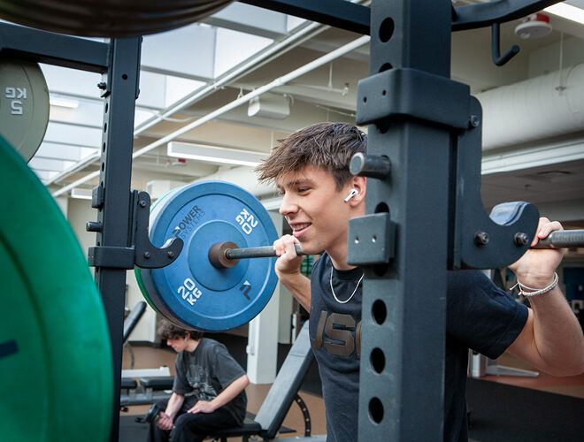 A student lifts weights in BC's Fitness Center.