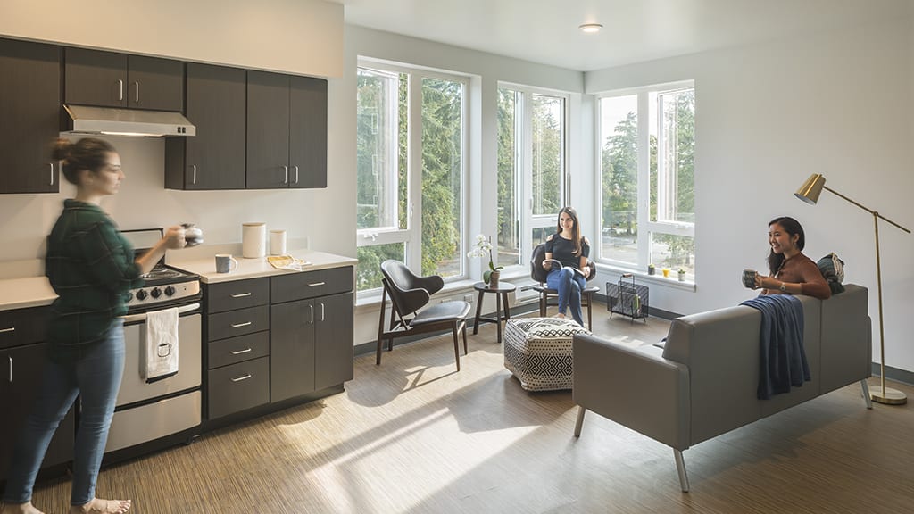 Students meeting in apartment kitchen and living area.