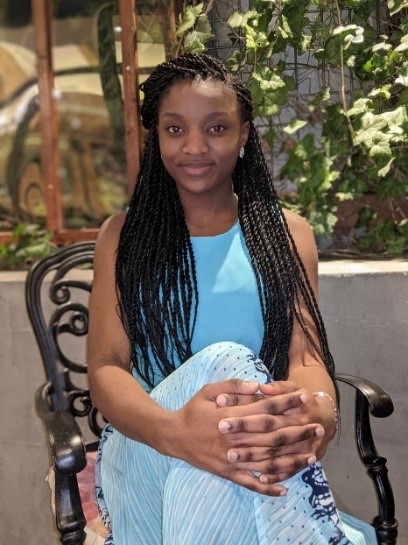 Smiling woman sitting on a chair with her hands clasped over her knees.