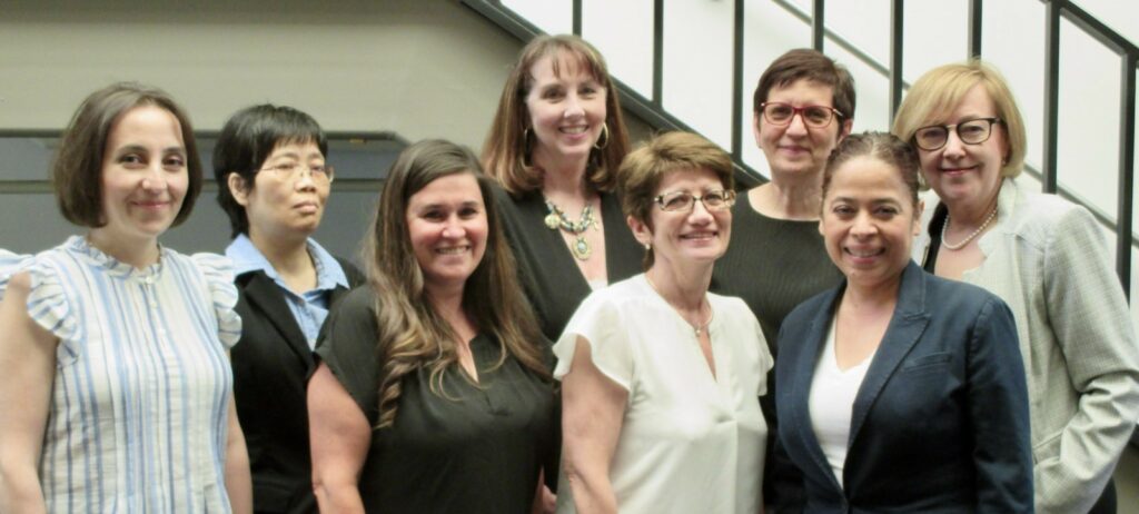 Eight members of the Payroll staff smiling in front of a staircase.