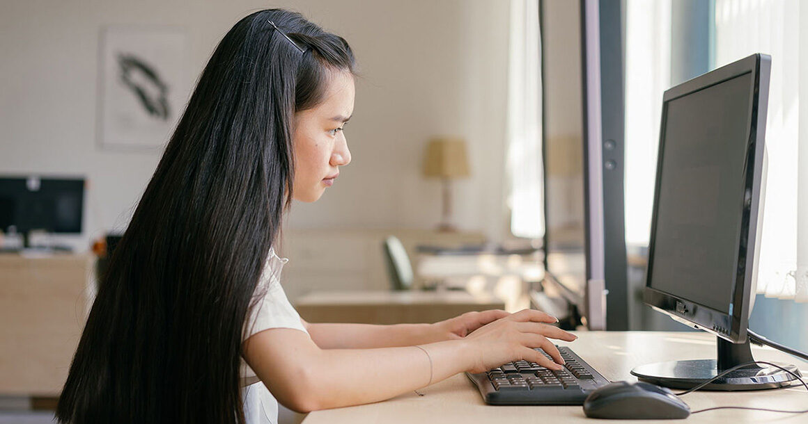 A student works on her computer by a window.