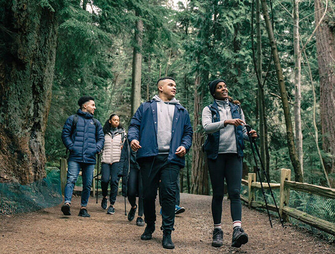 Six adults walking down a path in the forest