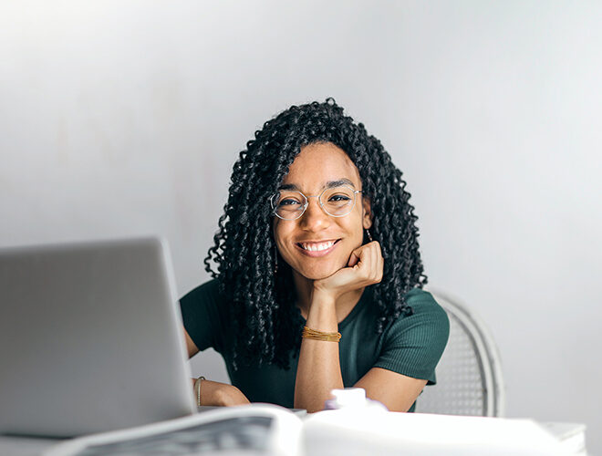 A student smiles in front of their laptop.