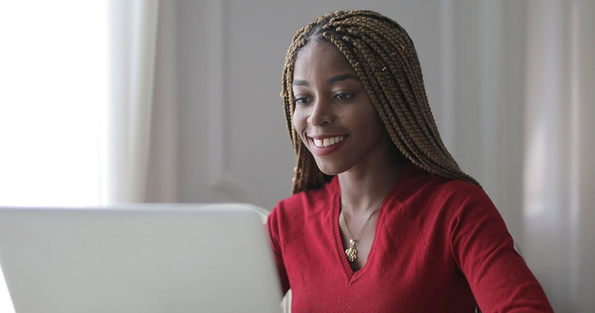 A smiling student works on a laptop.