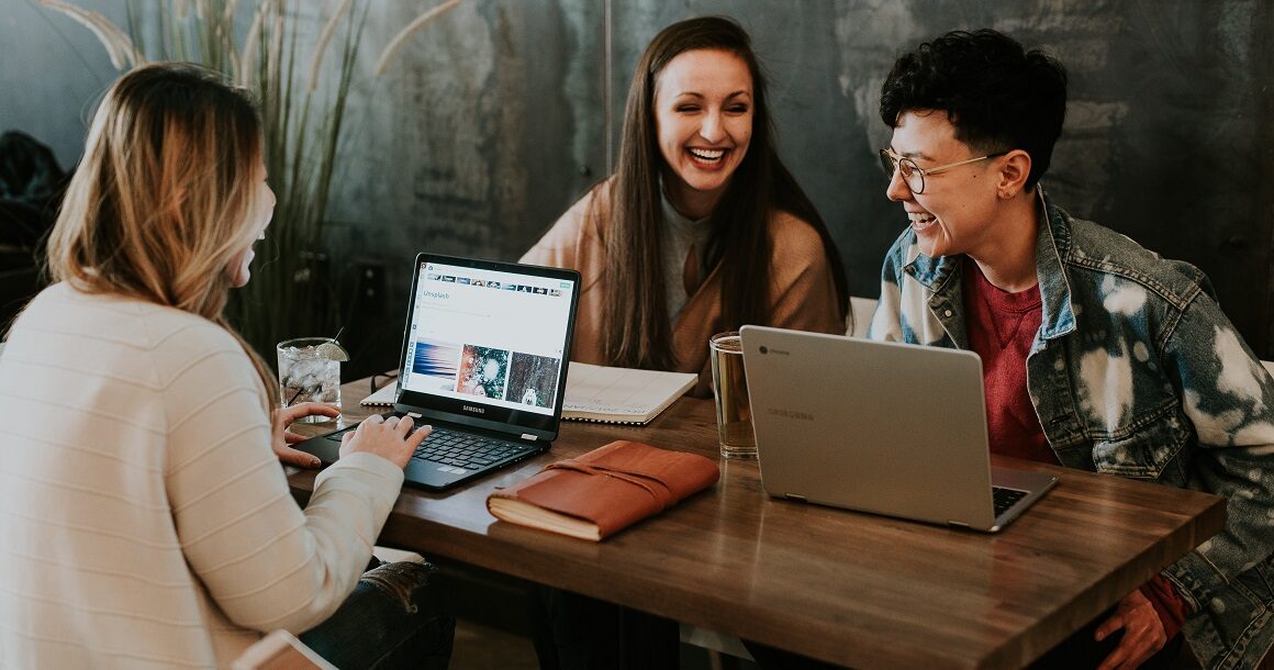 three students laughing at a table