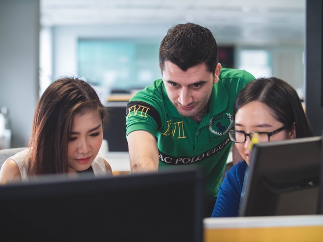 Three students looking at a computer monitor