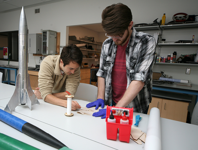 Two students collaborating together on a model rocket project.