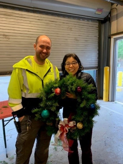 A man and woman holding a holiday wreath.