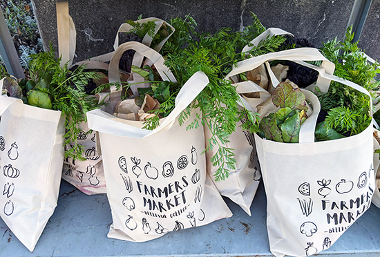 Custom BC-branded reusable bags are filled with produce.