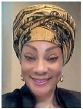 Dr. Alice smiling, wearing a yellow and black patterned headscarf and round earrings