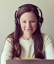 Cassie smiling with her arms crossed, wearing headphones and a white sweater