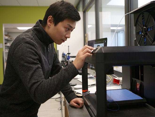 A student in a modern lab working on a 3d printer project.