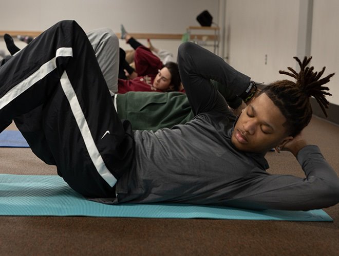 Students in a wellness class on yoga mats working on core exercises.