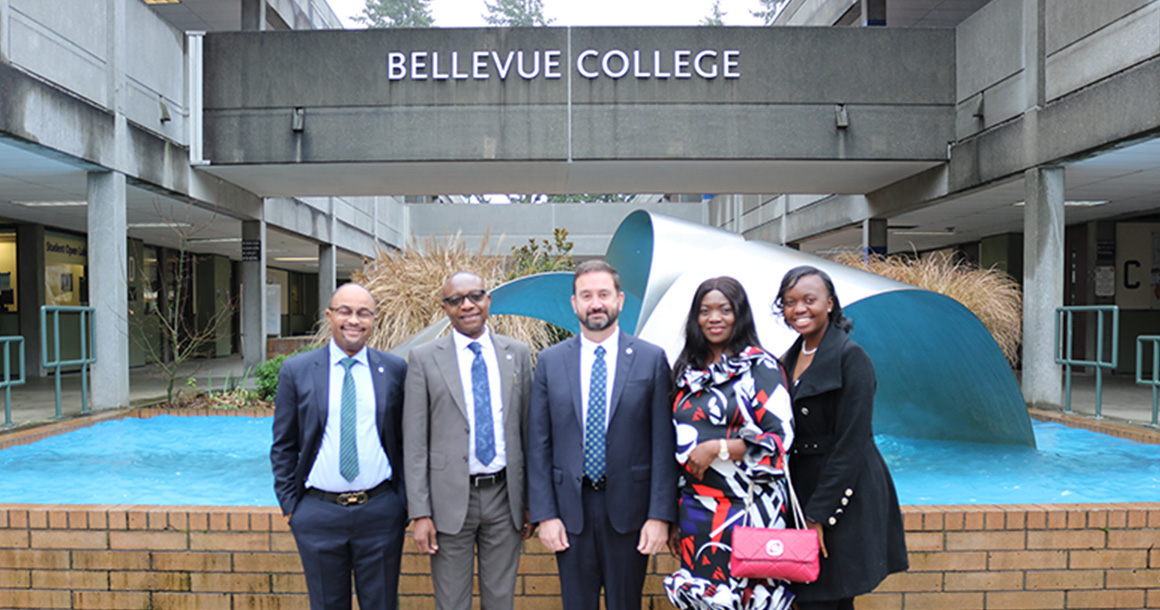 Four people pose for a photo in front of the Bellevue College fountain on campus.