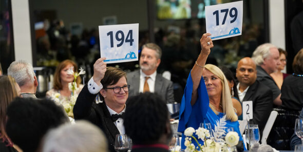 Two people hold up signs with numbers as they bid at last year's Bellevue College Foundation Gala.