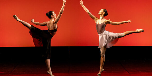 Two ballet dancers face each other in a pose. The background is red.