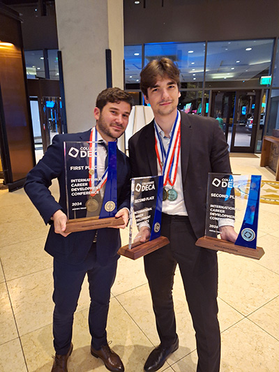 Two Bellevue College students pose with their DECA nationals trophies.