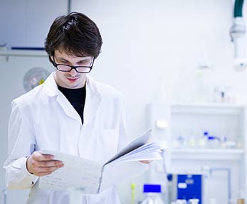 Lab scientist opens booklet of paper in a lab.