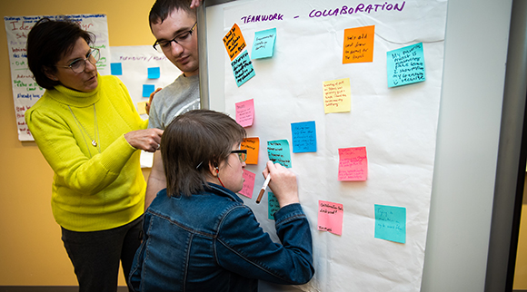 A professor guides OLS students as they add notations to a team project.