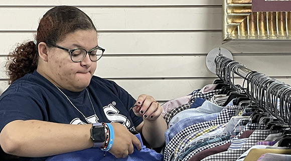 An OLS student hangs clothing at a thrift store.