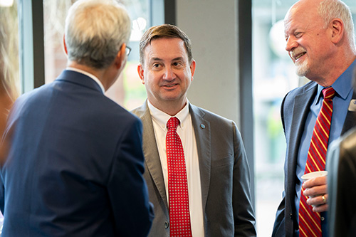 Two men look at other man as they chat. 