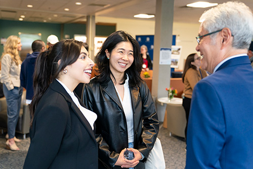 Three people smiling are looking at each other. 