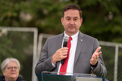 Man speaks with microphone at podium.