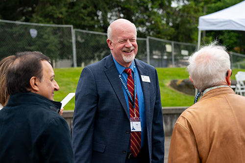 Man smiles at two people he's speaking with.