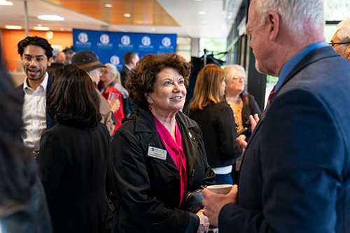 Two people chat with others in the background. 