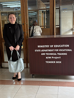 Judith Hernandez Chapar stands next to the Ministry of Education State Department for Vocational and Technical Training KfW Project, Tender Box.
